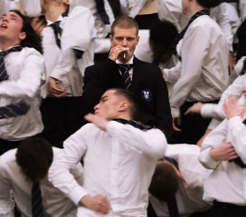 Still from the Storm music video: a crowd of students in uniform dancing